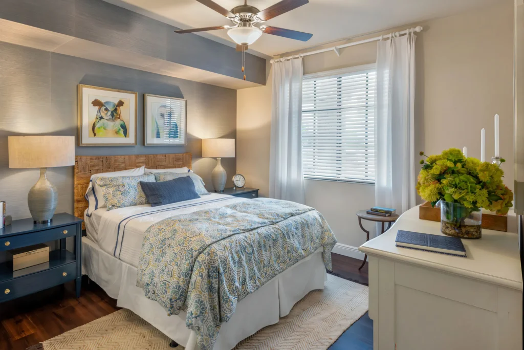 A modern sun-lit bedroom at The Ellery apartments in Plantation, designed for comfort and a relaxing lakeside lifestyle.