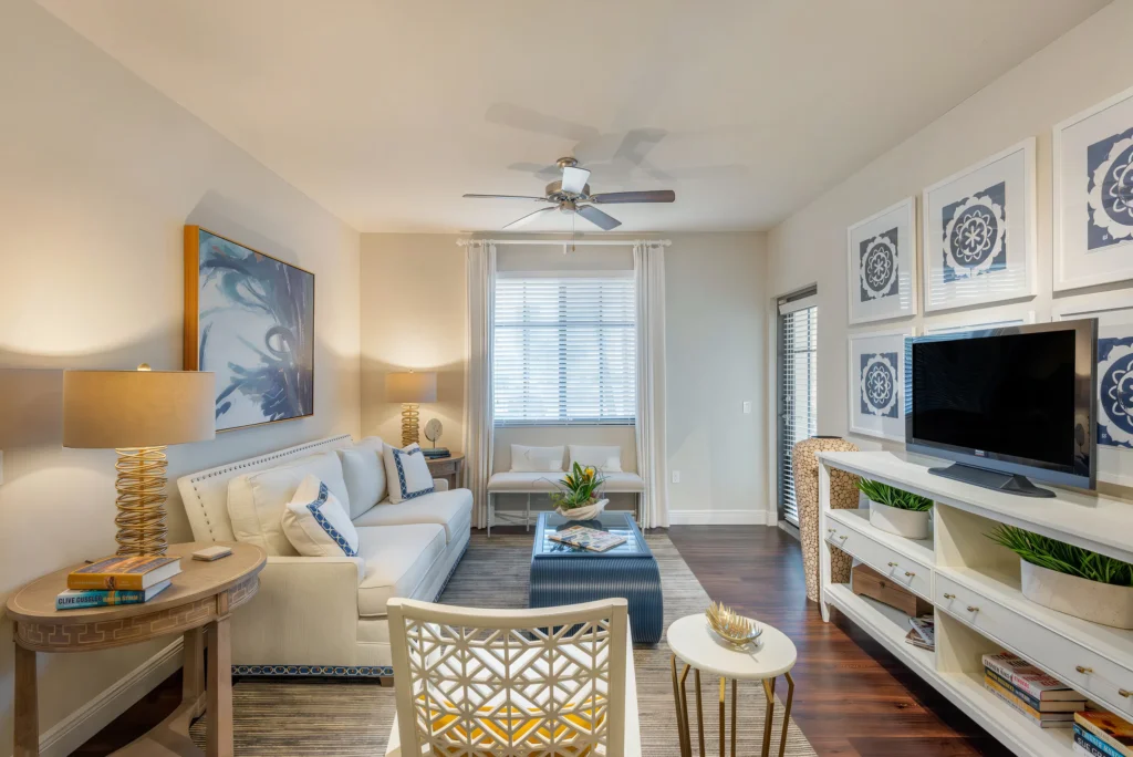 Bright and inviting furnished living area at The Ellery in Plantation, FL, showing a cozy seating arrangement and modern lakeside home design.